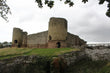 Round towers and curtain wall of Rhuddlan Castle seen from the dry moat, October 2026