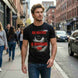 Man wearing a black t-shirt with 'Big Brother is Watching You' graphic on a city street.
