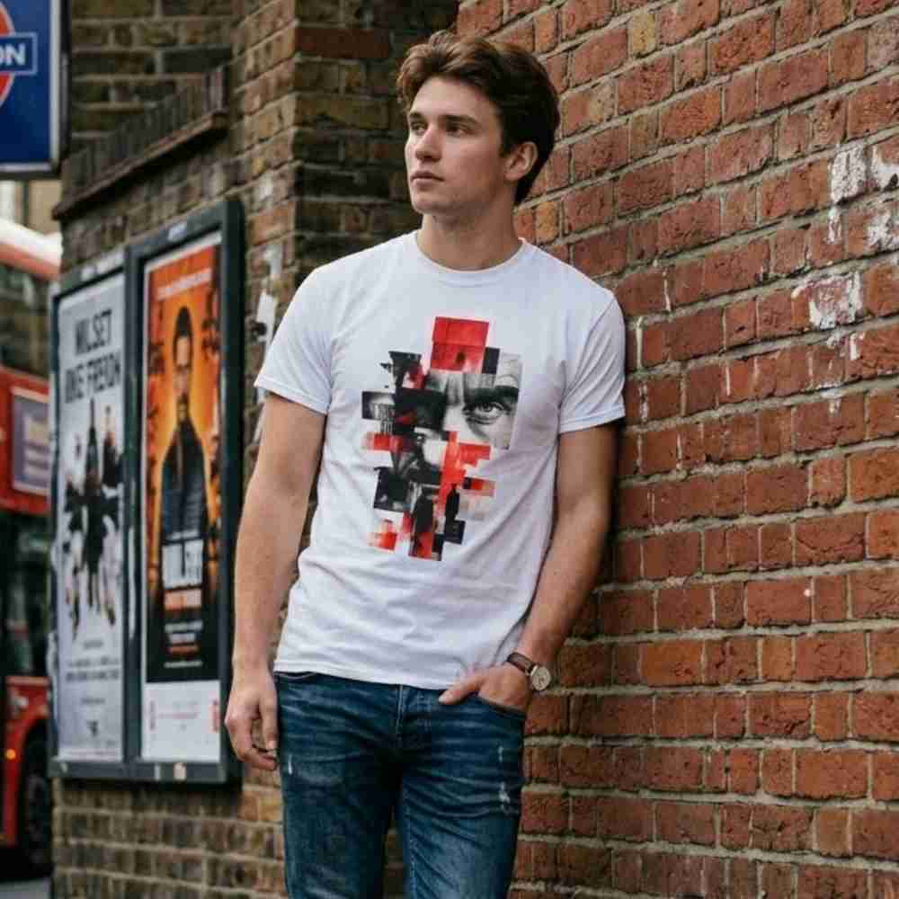 Man wearing a graphic t-shirt leaning against a brick wall with posters on a bus stop.