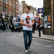 George Orwell 1984 T-Shirt worn by young man crossing a London road, with a black cab and red bus in the background