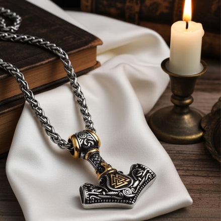 Viking-style necklace with hammer pendant on a white cloth with a candle in the background