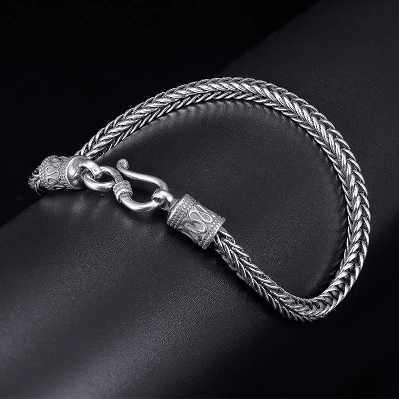 Silver braided bracelet with a clasp on a dark surface