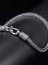 Silver braided bracelet with a clasp on a dark surface