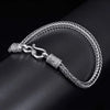 Silver braided bracelet with a clasp on a dark surface
