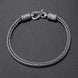 A silver-toned braided rope bracelet with a lobster clasp and decorative cylindrical end caps, photographed on a dark textured background.