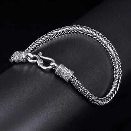 Silver braided bracelet with a clasp on a dark surface