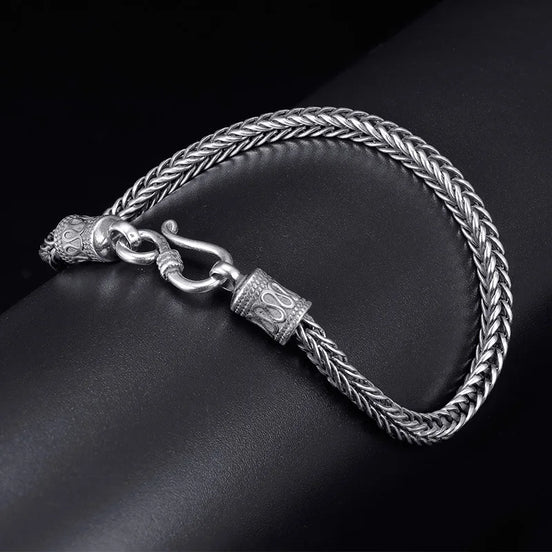 Silver braided bracelet with a clasp on a dark surface