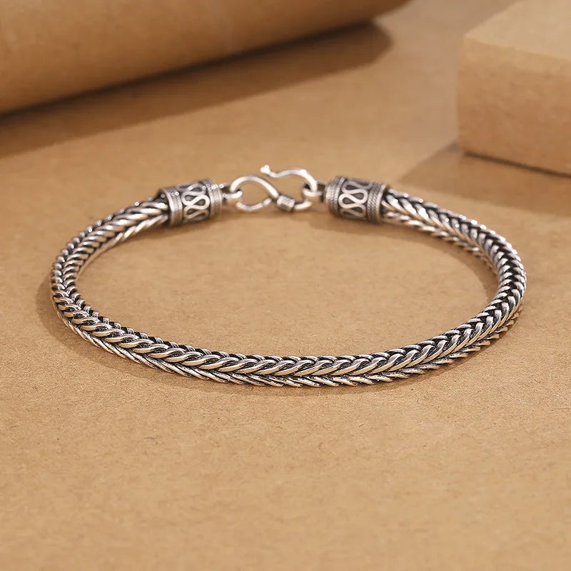 Silver braided bracelet on a brown background
