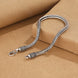 Silver braided necklace with clasp on a brown background