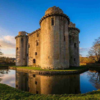 Ruins of a Nunney castle with a moat on a clear day