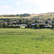 Green field with a village in the background under a blue sky.