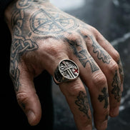 Hand with tattoos wearing a ring against a blurred background