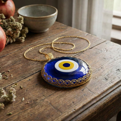 Evil eye pendant necklace on a wooden surface with apples and a bowl in the background