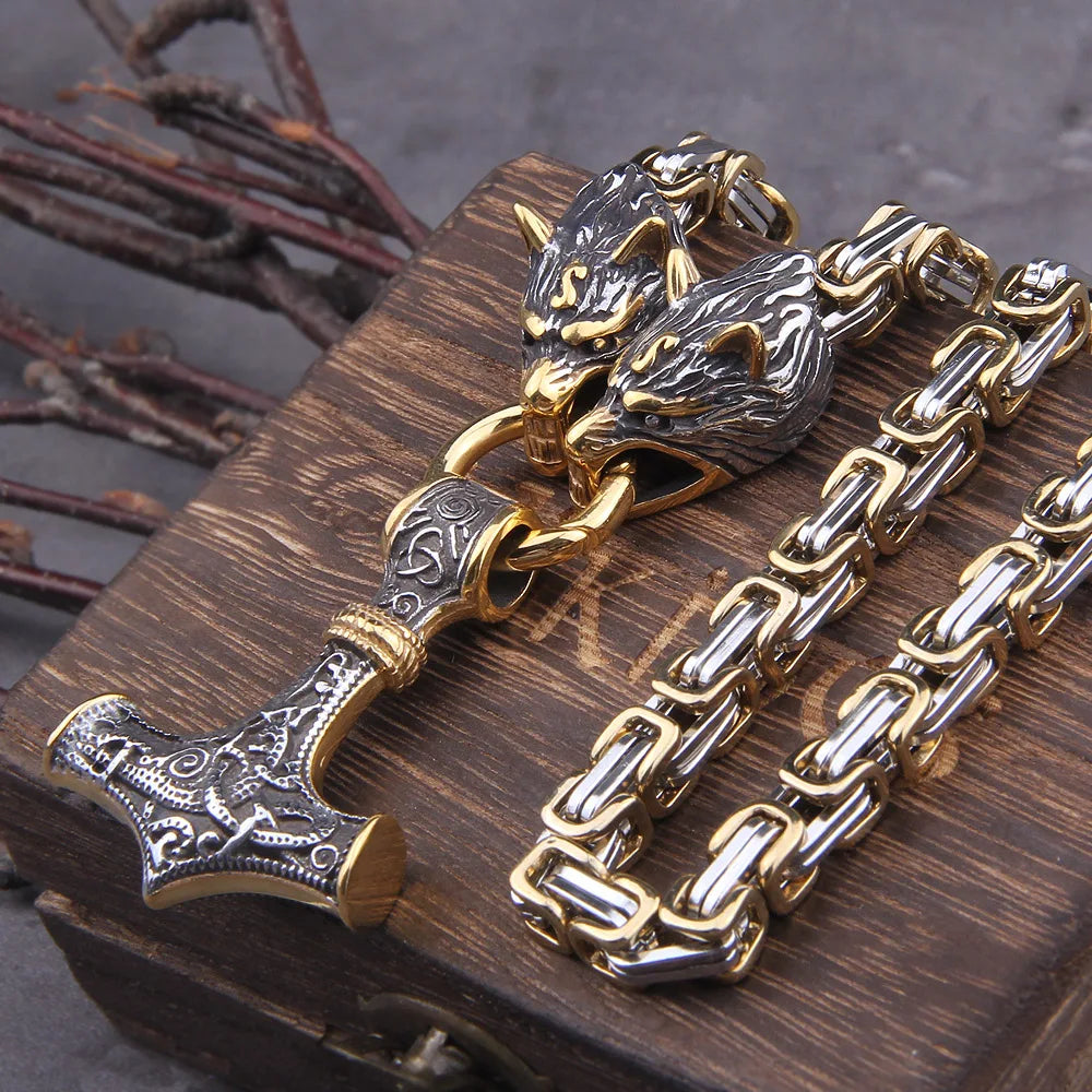 Gold and silver chain with wolf head and hammer design on a wooden surface