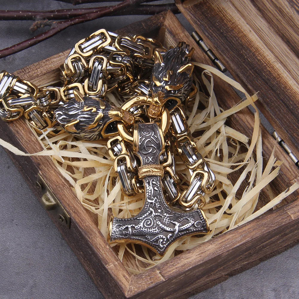 Gold and silver chain necklace with a detailed pendant on a wooden box.