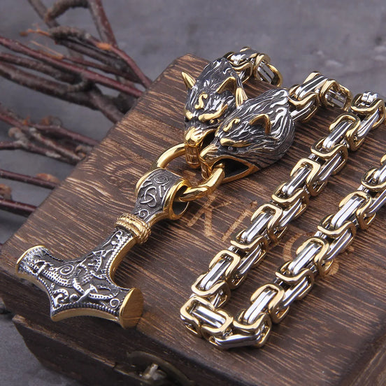 Gold and silver chain with wolf head and hammer design on a wooden surface