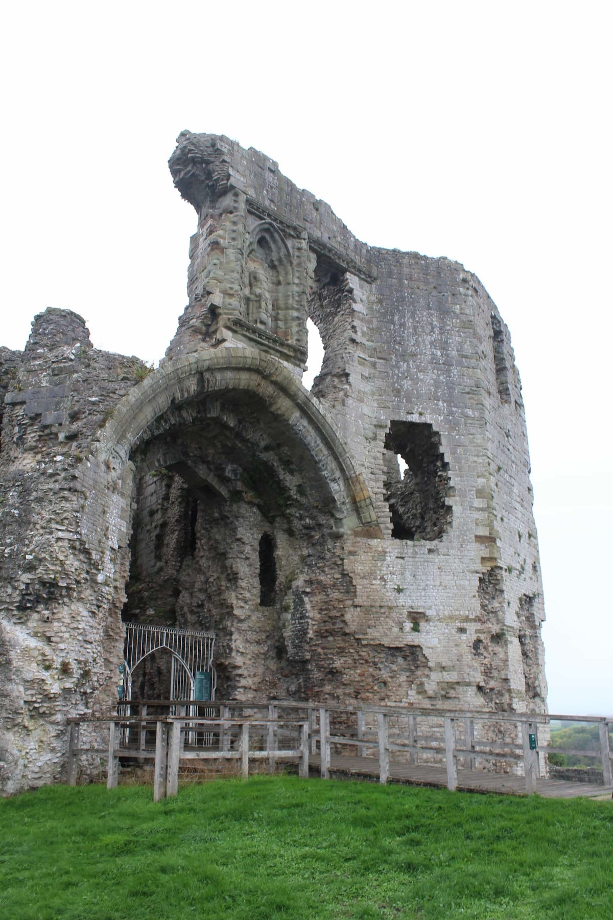 The great gatehouse of Denbigh Castle with the railed walkway leading to its entrance arch, October 2026