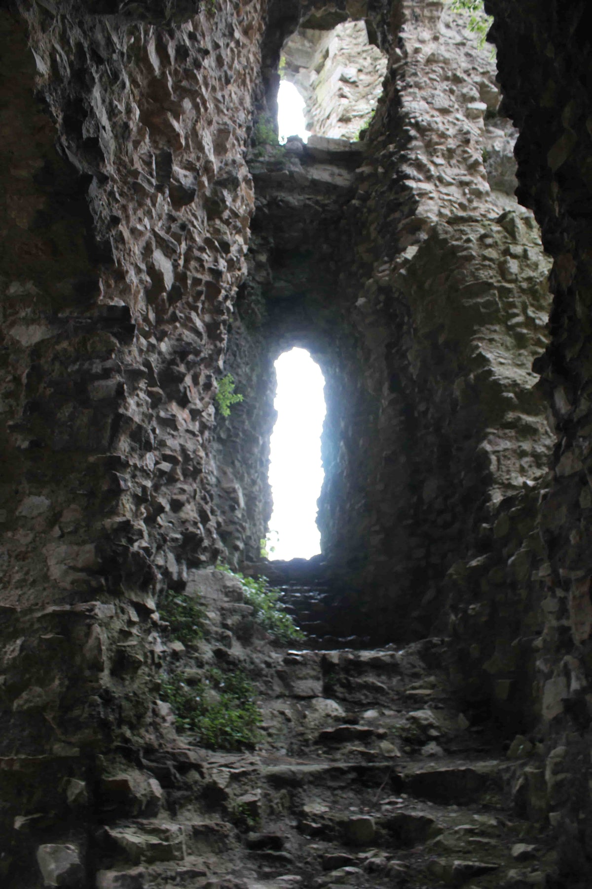 Narrow ruined stone stairway lit by a window slit inside Denbigh Castle, October 2026