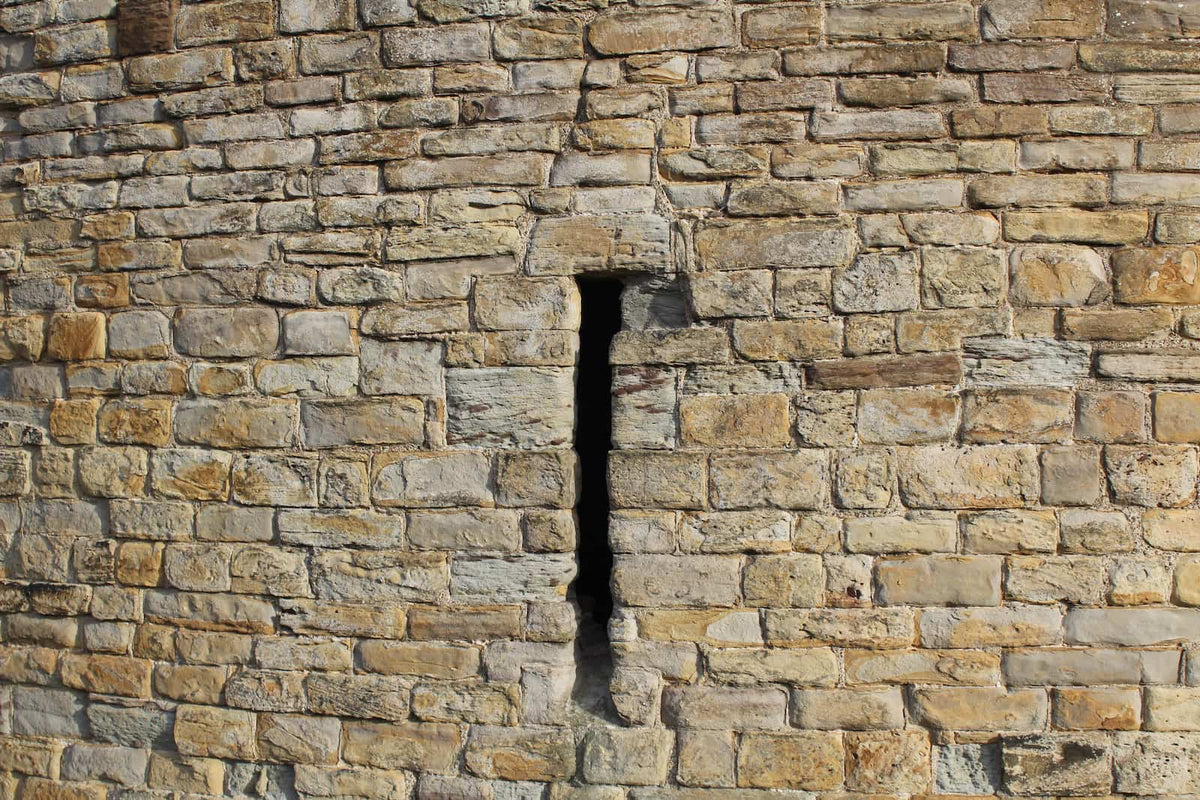 An arrow slit in the sandstone wall of Flint Castle, October 2026
