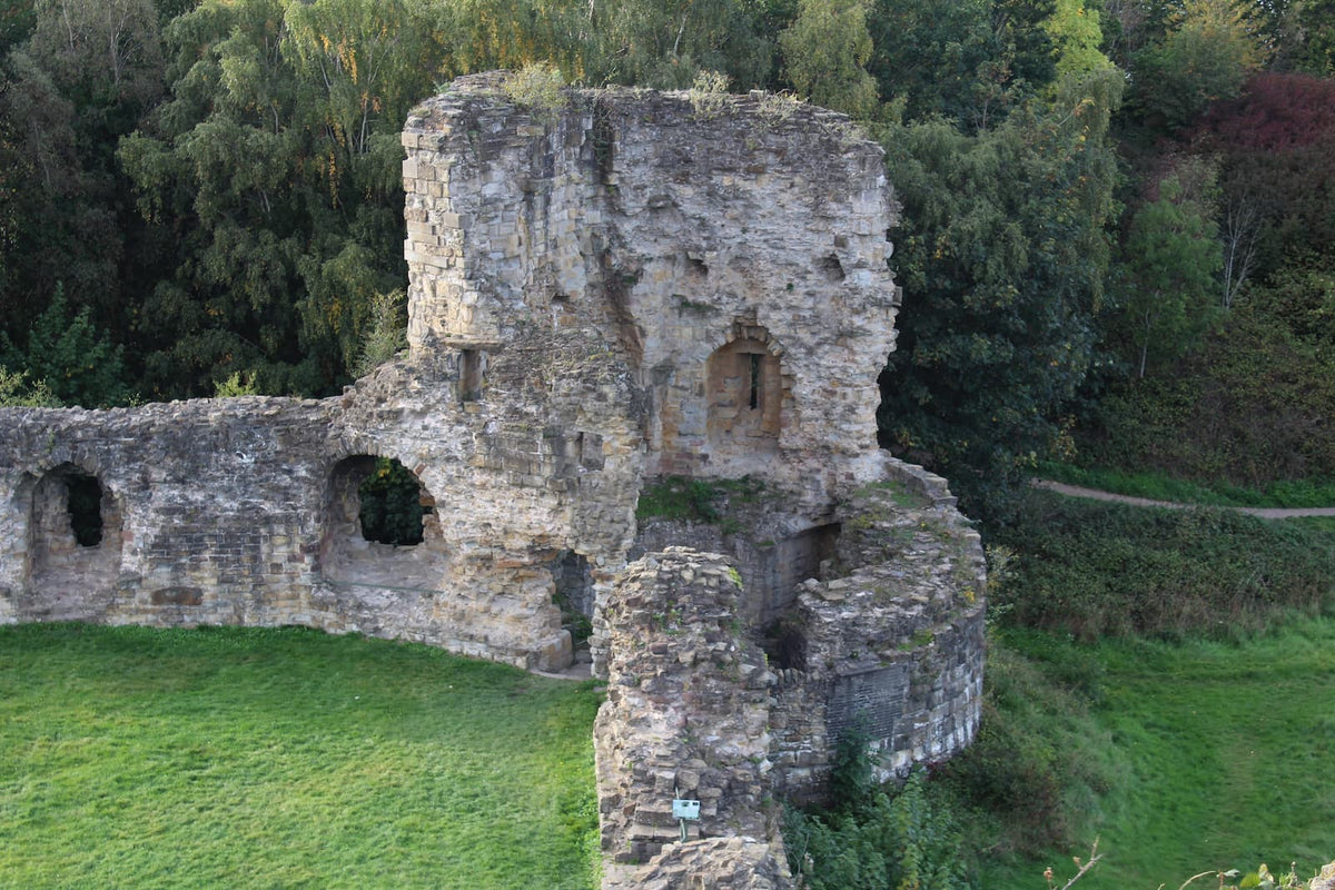 A corner tower and the curtain wall of Flint Castle seen from above, October 2026