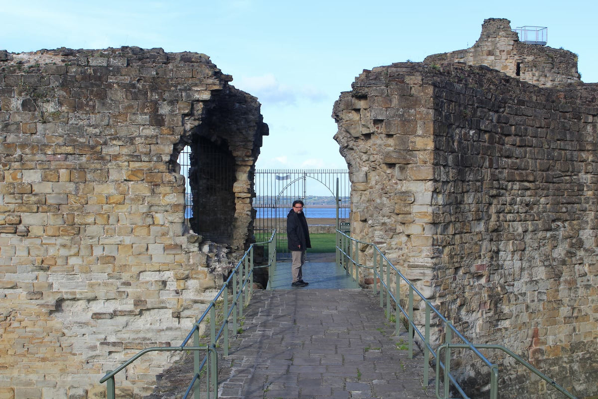 Simon A. Williams at the entrance gate of Flint Castle, with the Dee Estuary behind, October 2026