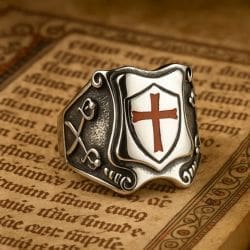 The Vintage Knights Templar Cross Ring features a shield design with a red cross and crossed swords, shown resting on an old manuscript with decorative script.