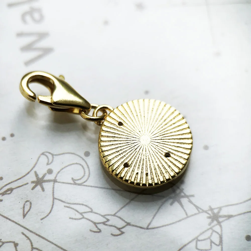 The Golden Lucky Coin Charm for Women, made of 925 sterling silver with a vintage pendant design, features engraved patterns, a central symbol, gemstones, and a lobster clasp.