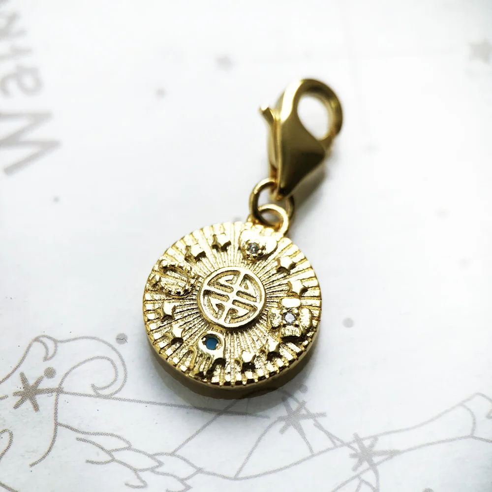 The Golden Lucky Coin Charm for Women, made of 925 sterling silver with a vintage pendant design, features engraved patterns, a central symbol, gemstones, and a lobster clasp.