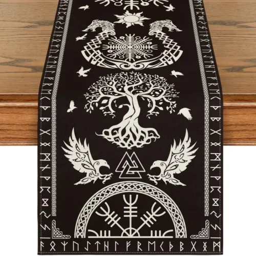The Viking Linen Table Runner | Nordic Table Décor in black, with white Norse-inspired designs—tree of life, ravens, wolves, runes, and geometric patterns—is displayed on a wooden table.